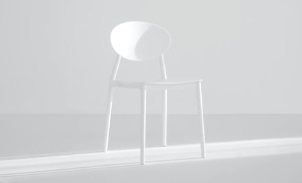 A single minimalist white chair standing in a bright, airy space.
